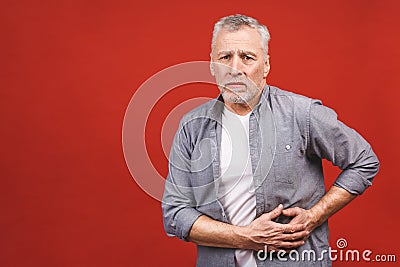 Senior aged man holds the liver. Pain in the abdomen. Cirrhosis of the liver. Closeup. Isolated against red background Stock Photo