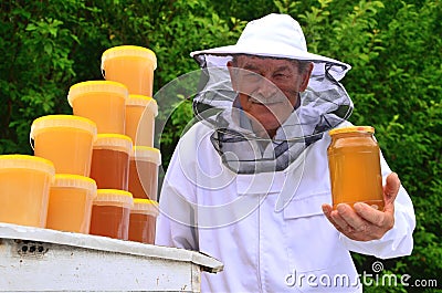 Senior apiarist presenting jar of fresh honey in apiary Stock Photo