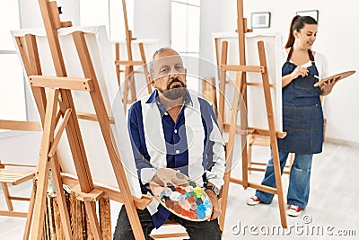 Senior artist man at art studio looking sleepy and tired, exhausted for fatigue and hangover, lazy eyes in the morning Stock Photo