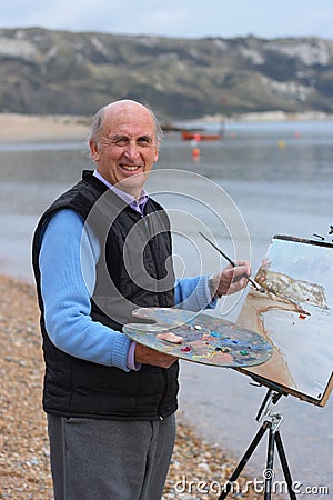 Senior artist painting by the sea. Stock Photo