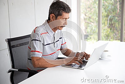 Senior Asia businessman in casual work by use laptop Stock Photo