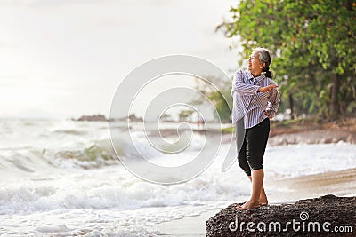 Senior Asia woman stretching on the beach Stock Photo