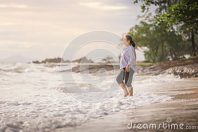 Senior Asia woman walking on the beach Stock Photo
