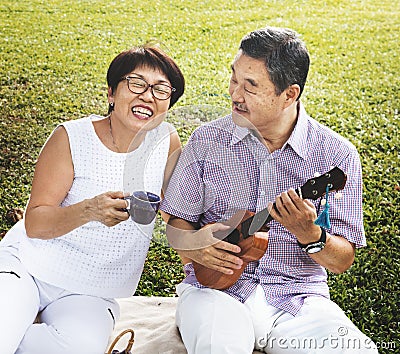 Senior Asian couple playing music in a park. Stock Photo