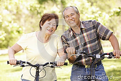 Senior Asian couple riding bikes in park Stock Photo