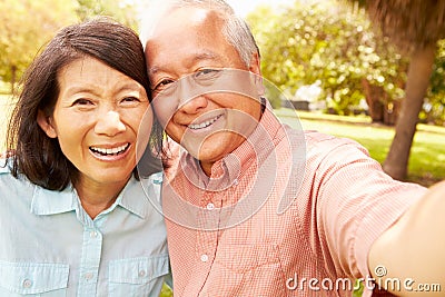 Senior Asian Couple Taking Selfie In Park Together Stock Photo