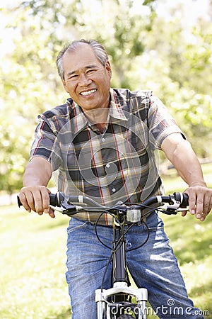 Senior Asian man riding bike in park Stock Photo