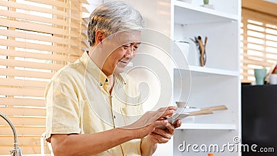 Senior asian man using smartphone at home background, Happy retirement asia male holding phone while standing in kitchen, Active Stock Photo