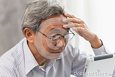 Asian old man glasses Headache from using and looking tablet screen Stock Photo