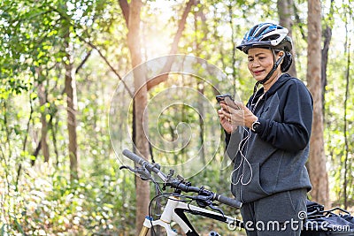 Senior asian woman bicycle in the park, With using smart phone Stock Photo