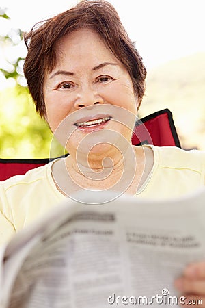 Senior Asian woman reading outdoors Stock Photo