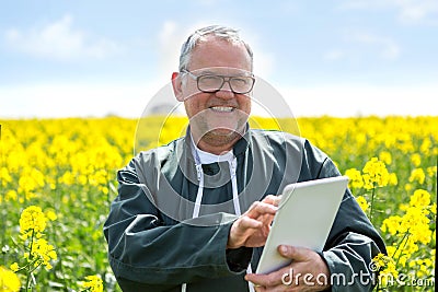 Senior attractive farmer working in a field helped by his tablet Stock Photo