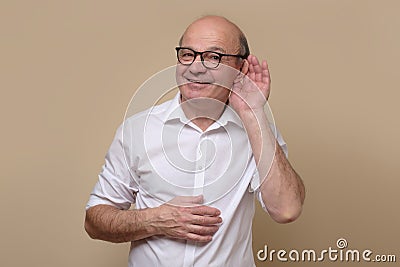 Senior bald male adult in glasses listening carefully, spying, being curious Stock Photo