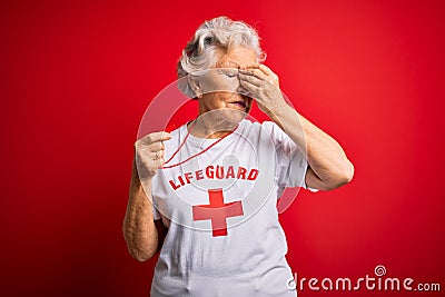 Senior beautiful grey-haired lifeguard woman wearing t-shirt with red cross using whistle tired rubbing nose and eyes feeling Editorial Stock Photo