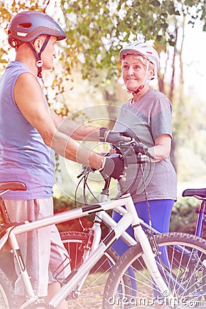 Senior bicycle rider looking at senior man in park Stock Photo