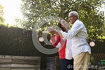 Senior black couple dancing in their back garden Stock Photo