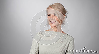 Senior blonde woman is toothy smiling looking away isolated Stock Photo