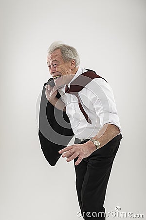 Senior businessman leaning forwards into wind Stock Photo