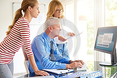 Senior businessman sitting in front of computer with his team. Teamwork. Stock Photo