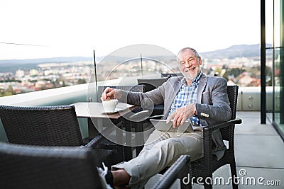 Senior businessman working on tablet in rooftop cafe Stock Photo