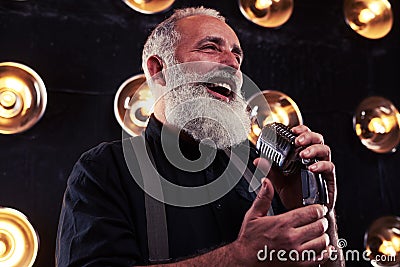 A senior Caucasian bearded man with microphone singing jazz Stock Photo