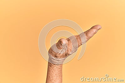 Senior caucasian hand over yellow isolated background with flat palm presenting product, offer and giving gesture, blank copy Stock Photo