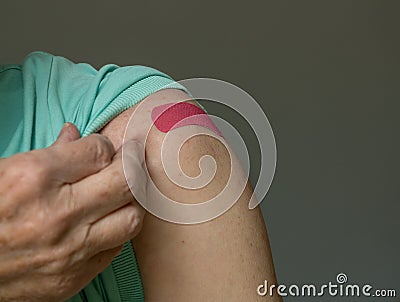 Senior man holding up shirt after covid-19 vaccine injection Stock Photo