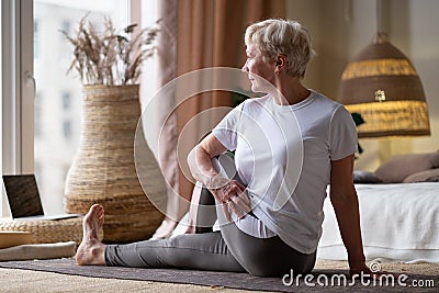 Senior caucasian woman in half spinal twist pose on mat Stock Photo