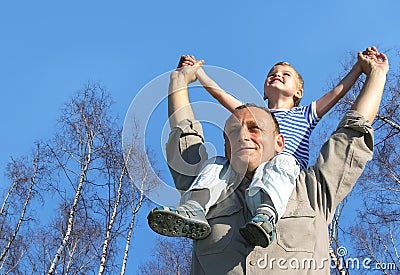 Senior with child on shoulders in front of birch Stock Photo