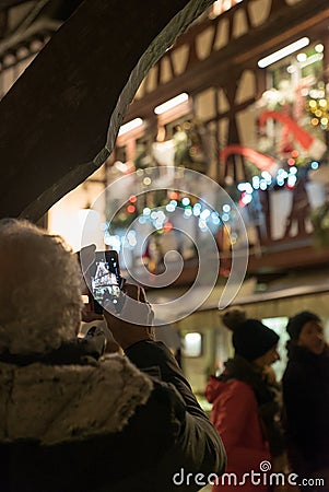 Senior citizen taking a photo with cell phone of beautifully decorated half-timbered houses in La Petite France in historic Editorial Stock Photo