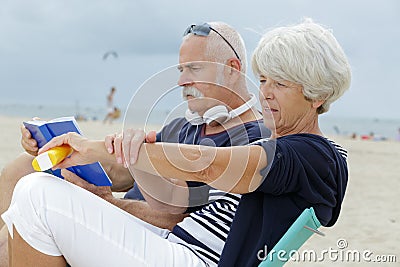 senior couple on beach woman applying suncream Stock Photo