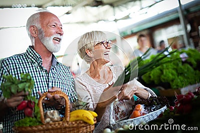 Senior couple buying fresh vegetables and fruits at the local market Stock Photo