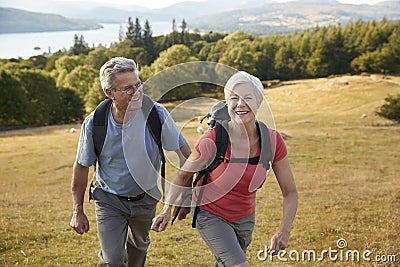 Senior Couple Climbing Hill On Hike Through Countryside In Lake District UK Together Stock Photo