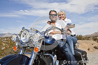 Senior couple on desert road sitting on motorcycle looking at camera Editorial Stock Photo