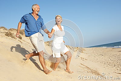 Senior Couple Enjoying Beach Holiday Running Stock Photo