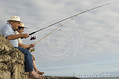 Senior Couple Fishing Against Cloudy Sky Stock Photo