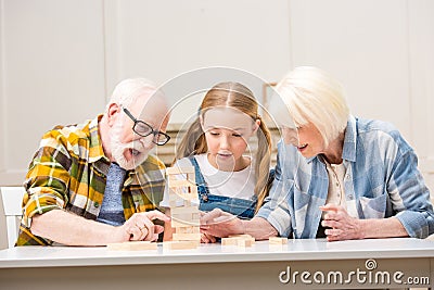 Senior couple with granddaughter playing jenga game at home Stock Photo