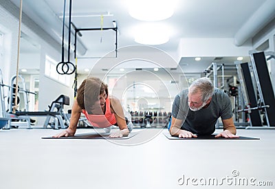 Senior couple in gym in plank position working abs Stock Photo