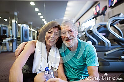 Senior couple in gym sitting in front of treadmills Stock Photo
