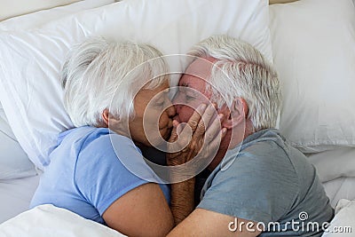 Senior couple kissing each other in bedroom Stock Photo