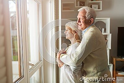 Senior couple looking out living room window Stock Photo