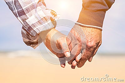 Senior couple in love walking at the beach holding hands Stock Photo