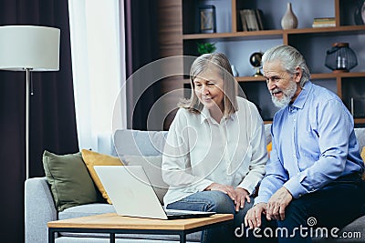 Senior couple man and woman shopping online browsing laptop in home. Elderly family Happy retired couple using computerooking at Stock Photo