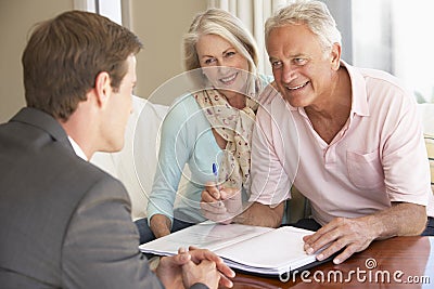 Senior Couple Meeting With Financial Advisor At Home Stock Photo