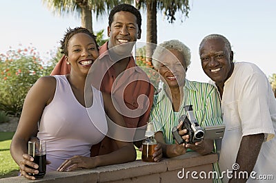 Senior couple and mid-adult couple senior woman holding camcorder portrait. Stock Photo