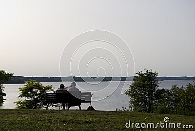 Senior couple on a park bench on a summers evening. Stock Photo