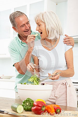 Senior Couple Preparing Salad In Kitchen Stock Photo