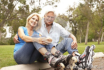 Senior Couple Putting On In Line Skates In Park Stock Photo