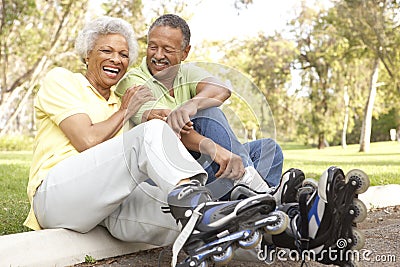 Senior Couple Putting On In Line Skates In Park Stock Photo