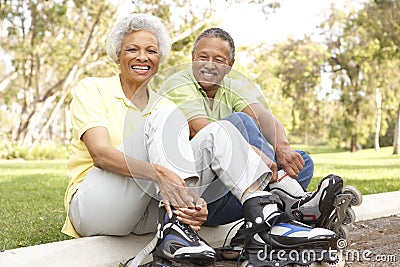 Senior Couple Putting On In Line Skates In Park Stock Photo